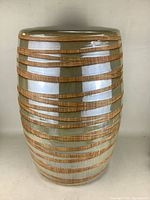 Front view of large ceramic stool with horizontal carved grooves and glossy finish