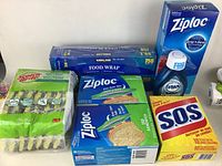 Full view of the lot showing Ziploc bags, Kirkland food wrap, Dawn Ultra Platinum Powerwash spray refill, S.O.S steel wool soap pads, and Scotch-Brite sponges.