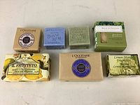 Seven new soap bars arranged on a white surface, showing labels and packaging detail.