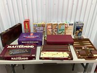 Wide view of entire lot showing all games on table including Mastermind, Balderdash, card games, and game cases.
