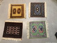 Four vintage hand knotted wool miniature rugs laid out on the floor showing varied colors and fringed edges.