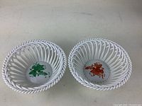 Pair of white porcelain baskets with lattice weave design, green and orange floral decorations inside, front view