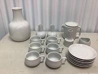 Full view of the tea set including tea pot, cups, saucers, plates, vases, creamer, and large vase.