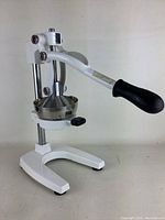 Side view of the manual juicer showing the lever handle, enameled base, and pressing cone.