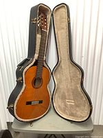 Full view of Yamaha acoustic guitar inside the open hard case standing upright on a table