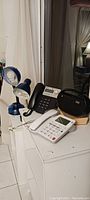 Photo of office phones, blue base lamps, and office radio on white furniture surface.