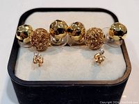 Photo showing the full set of earrings in the box, featuring larger round gold earrings with faceted and filigree textures and smaller stud earrings with clear stones.