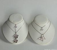 Full view of both necklaces on display stands showing the pendant designs clearly