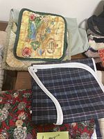 Photo showing yellow floral quilted potholder, blue and white plaid potholder, and floral fabric items underneath