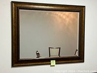 Front view of the rectangular wall mirror showing beveled glass and ornate brown frame with carved details.