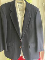 Front view of navy blue men's sport coat with white dress shirt underneath, showing lapels, buttons, and pockets