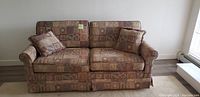 Front view of patterned fabric hide-a-bed sofa with two cushions
