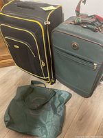 Photo showing two medium rolling suitcases side by side and a green tote bag in front