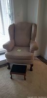 Wing back chair and ottoman positioned near a glass door showing front view