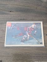Photo of the front side of the 1954-55 Parkhurst hockey card number 89 featuring Floyd Curry in an ice hockey game scene.