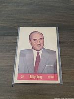 Front side of the 1957-58 Parkhurst Billy Reay hockey card #25 showing a color portrait of Billy Reay the coach, in a suit and red tie.