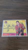 Front image of 1968-69 OPC hockey card showing Stan Mikita in Chicago Blackhawks uniform with an action hockey scene in yellow background.