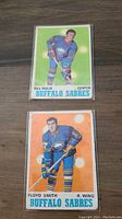 Front view of two hockey cards showing Bill Inglis and Floyd Smith in Buffalo Sabres uniforms from 1970 O-Pee-Chee set.
