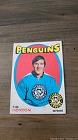 Front side of 1971 OPC hockey card showing Tim Horton in Pittsburgh Penguins blue jersey with team logo, set title, and player info.