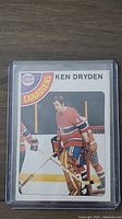 Front side of 1978 OPC Ken Dryden hockey card in protective sleeve showing player image and team logo.