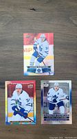 Photo of three Auston Matthews hockey cards on a wooden surface showing different styles and editions.
