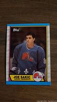 Front color photo of Joe Sakic in Quebec Nordiques uniform on 1989 Topps hockey card.