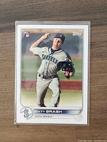Photo of front facing Matt Brash rookie baseball card in protective sleeve showing player in pitching motion wearing Seattle Mariners uniform.