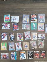 Top-down view of 29 Montreal Canadiens hockey cards arranged on a wooden floor showing a variety of players, different card designs including vintage styles and modern prints.
