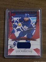 Front of hockey card showing Nick Robertson in Toronto Maple Leafs uniform, with embedded blue fabric patch.