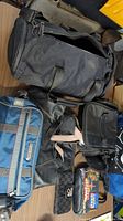 Six bags shown including black duffle bag, blue Tommy Hilfiger bag, black purse, black handbag with pink interior, and smaller bags.