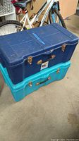 Two stacked Contico plastic storage trunks, one blue on top and one turquoise beneath, showing general wear and metal clasps.