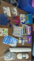 Wide view of crafting materials arranged on table including scissors, stickers, stamps, ink pads, yarn, and other supplies