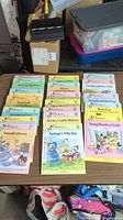 Long view of 22 Disney children's books arranged on table showing different titles and colorful illustrated covers featuring Disney characters.