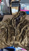 Photo of the full faux fur coat showing the texture, hood, and overall style on a table.