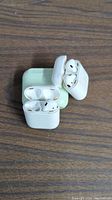 Photo of two Apple AirPods charging cases with earbuds inside, one case is white and one shows wear