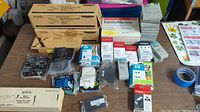 Wide view of all items on table showing Xerox maintenance kits, HP ink cartridges, and other printer supplies.