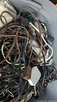 Photo showing tangled assortment of wires, cables, a brown power strip, power cords inside a grey plastic tote.