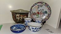 Overall collection of Asian themed dishes, bowls, and cups on a white surface
