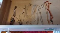 Full view of 9 necklaces in drawer showing variety of bead styles and chains.