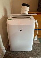 Front view of white LG portable air conditioner with control panel and exhaust vent opening on top.