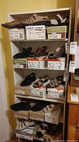 Shelf displaying five pairs of shoes along with boxes. Shoes include beige Romika sandals on top, brown leather Rieker shoes, and other various brands in neutral tones.