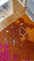 Overview of the silver jewelry collection laid out on a multicolored rug showing rings, bracelets, necklaces, pendants, and earrings.