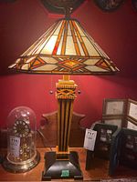 Frontal view of the lamp on a wooden desk with a glass dome clock and frames visible.