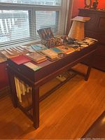 Full length side view of wooden console table against window, showing height and length with feet and supports visible.