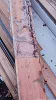 Closeup of wooden plank edge with remnants of wrapping and some damage or wear