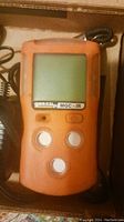 Orange handheld gas detector labeled 'gasclip MGC-IR' with screen and three control buttons, showing front view of device.