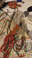 Necklaces spread out on a patterned fabric surface showing various styles and materials including chunky chains, beads, and pendants.