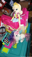 My Little Pony fairy princess doll sitting on bright pink plastic dollhouse with white unicorn toy in front
