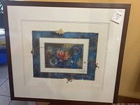 Framed abstract artwork with layered rectangles, including a central piece with mostly blue, white, gold, and red colors.