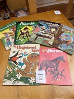 Six oversized kids books laid out on a table showing covers: Bambi, Cinderella, Those Cats, The Gingerbread Man, Know Your Horses, and another book partially visible.